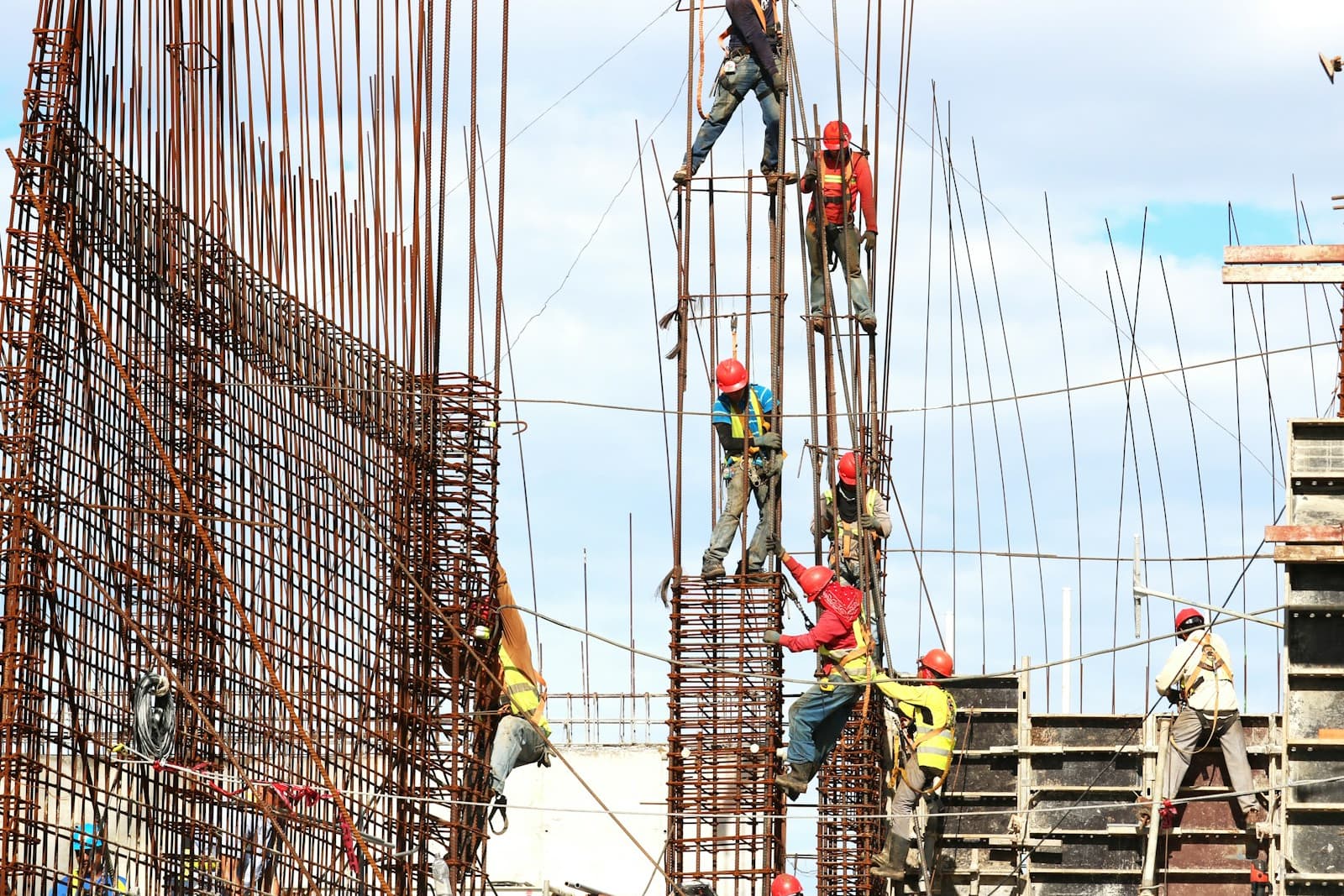 Workers tying vertical steel reinforcing bar for a concrete structural wall